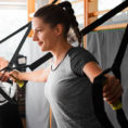 Two people exercising using TRX equipment in gym