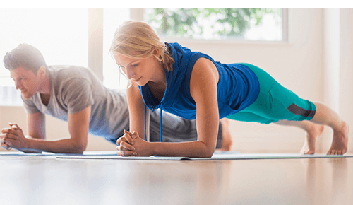 People strengthening their core performing plank exercise on yoga mats
