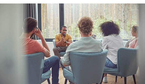 Group of people talking while seated in chairs in a circle
