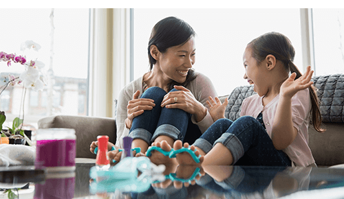Mother and daughter painting their toenails together on the couch