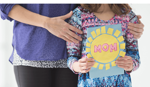 Closeup of an adult and a girl holding a Mother's Day card
