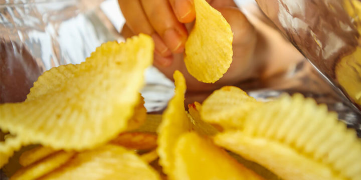 Closeup inside of potato chip bag as a hand pulls out a potato chip