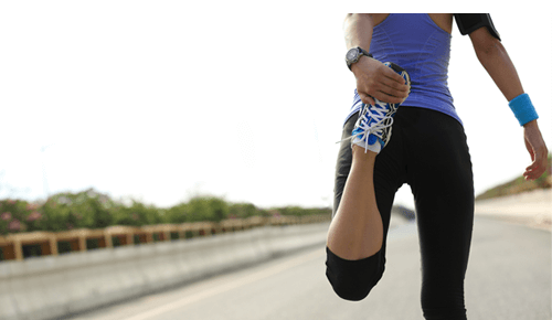 Person stretching leg while on a run outdoors