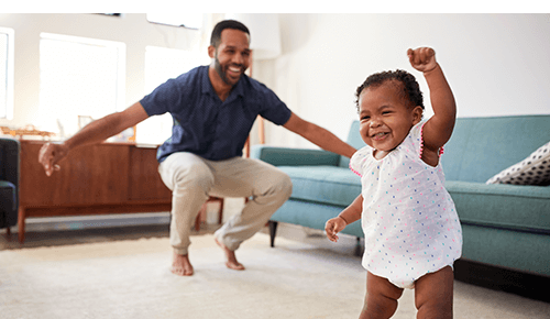 Father and baby dancing together in living room