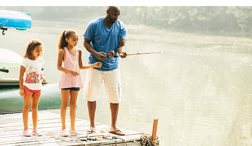 Father and Daughters Fishing on dock at lake