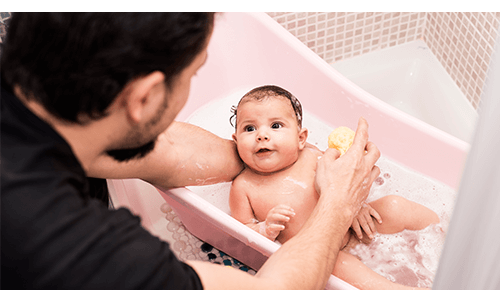 Dad cleaning a baby in a small bath