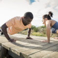 Two people exercising performing push ups outside
