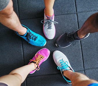Closeup of a group of people's feet wearing different colored running shoes