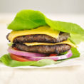 Two burger patties with cheese in a lettuce wrap, no bun