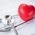 Red heart next to stethoscope on top of heart rate graph