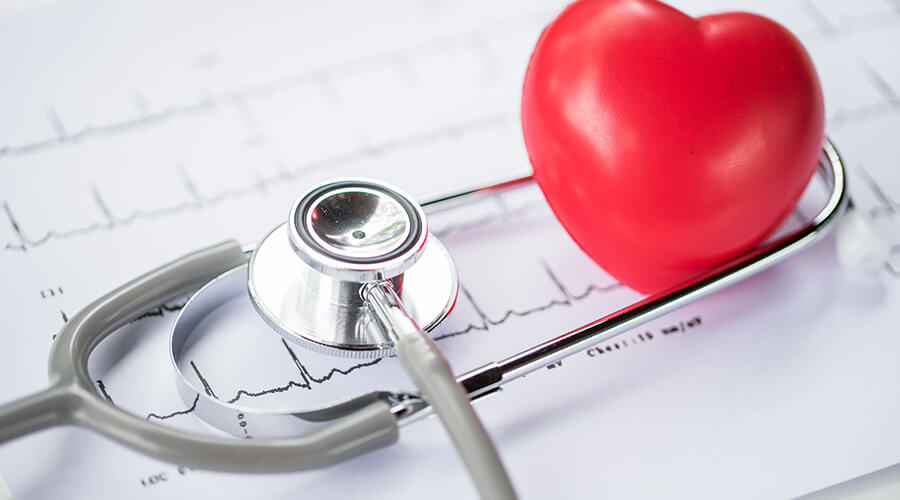Red heart next to stethoscope on top of heart rate graph