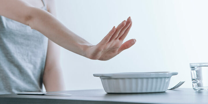 Person putting their hand up as if saying no to a container of food