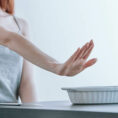 Person putting their hand up as if saying no to a container of food