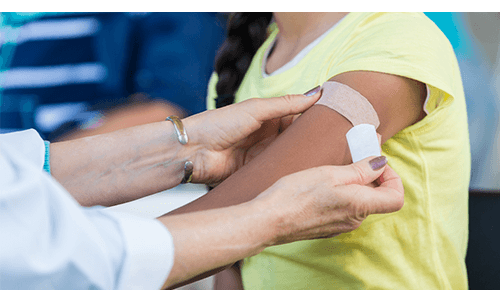 Doctor putting a bandaid over a vaccine site on an arm