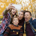 Family outside during the fall making funny faces while taking a picture of themselves