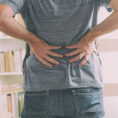 Closeup of person holding their lower back in pain