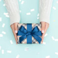 Person holding gift wrapped in blue bow and paper