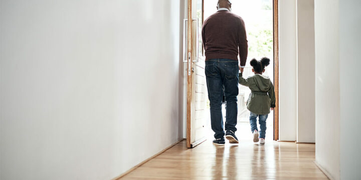 Adult and small child walking out front door holding hands
