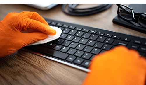Person cleaning and disinfecting a computer keyboard