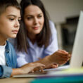 Mother helping child with homework on laptop computer