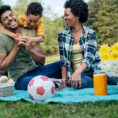 Parents and child sitting outside on a blanket having a picnic