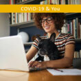 Woman holding dog working on laptop computer