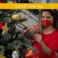 Woman wearing face mask decorating Christmas tree