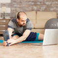 Man exercising while looking at laptop for workout guidance