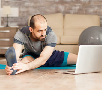 Man exercising while looking at laptop for workout guidance