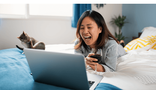 Woman chatting on a virtual call on her computer with a glass of red wine