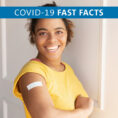 Smiling person holding up arm with band-aid on it