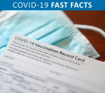 Proof of vaccine card sitting next to mask