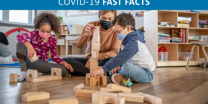 Two children wearing masks while playing blocks with a masked adult
