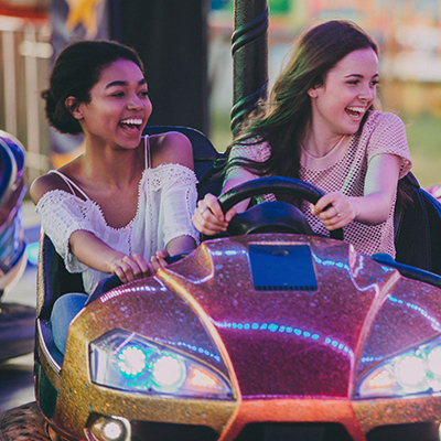 Two girls driving bumber cars at a festival