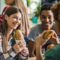 Group of young adults eating sandwiches