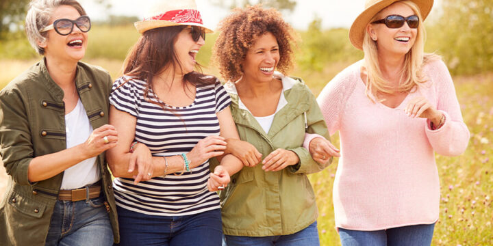 Four middle-aged people smiling while walking outside