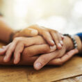 Close up of two people holding hands in comfort