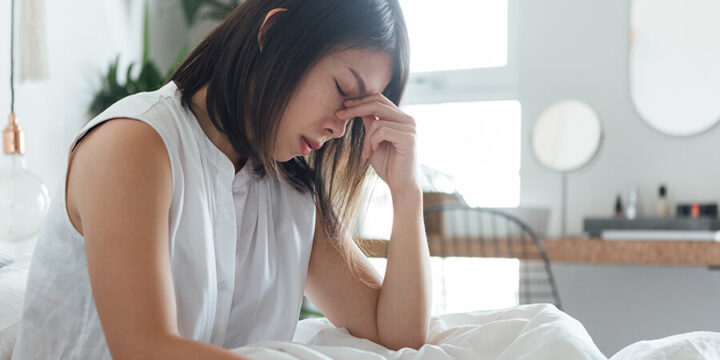 person sitting with hand to forehead looking exhausted