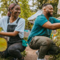 man and woman kneeling while gardening and laughing
