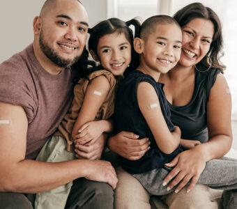 Family smiling with band-aids on their arms from receiving a vaccine shot