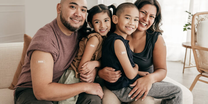 Family smiling with band-aids on their arms from receiving a vaccine shot