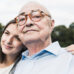 Older person looking at camera while younger person leans on their shoulder