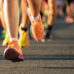 Close up of runner's feet in motion in front of a group of other people running