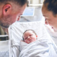 Parents looking down at their newborn baby in the hospital