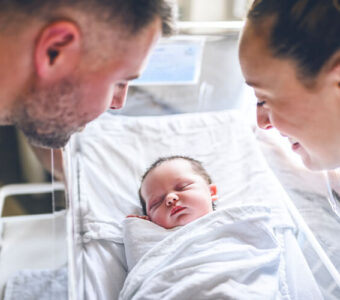 Parents looking down at their newborn baby in the hospital