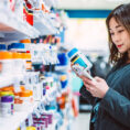 Woman shopping for supplements at the pharmacy, researching on phone