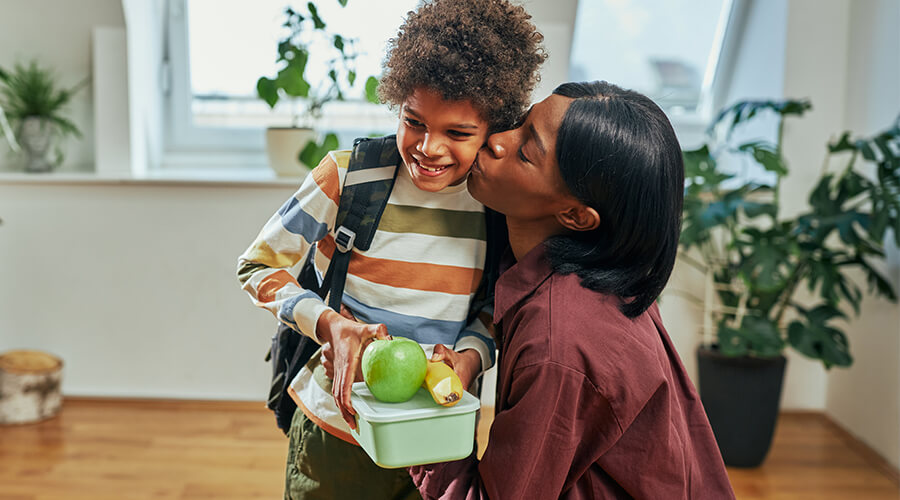 Mom kissing child on cheek before child goes to school