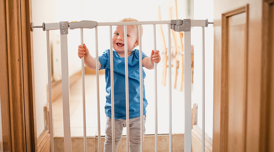 child holding onto baby gate in home
