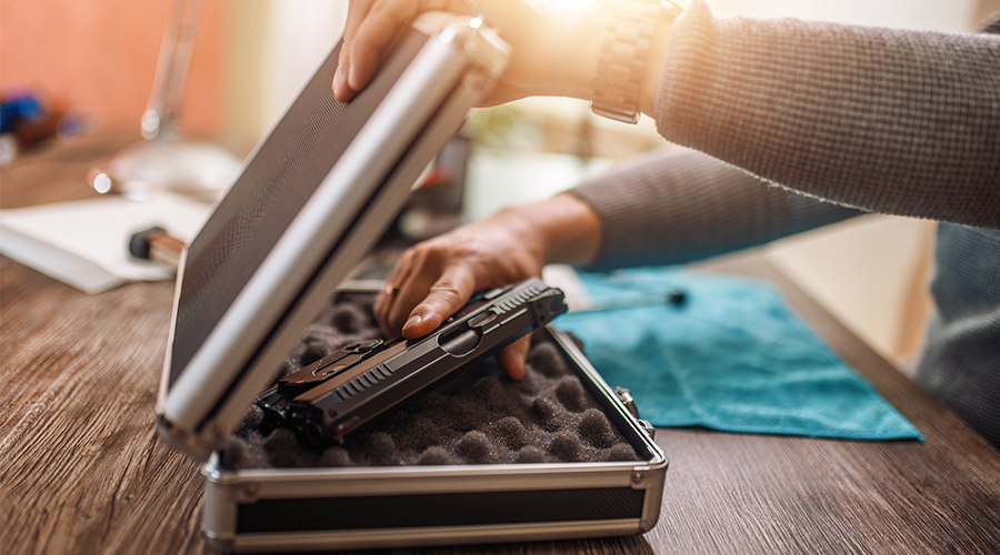 Close up of person putting gun in a secure gun lock box