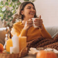 Woman sitting on sofa with blanket and drink